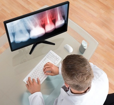 A dentist examining an X-ray on a computer.