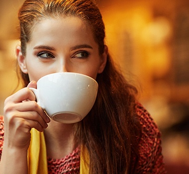 A woman drinking from a mug.