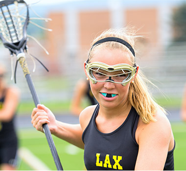 Teen girl playing lacross with blue sportsguard