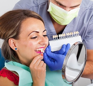 woman in red shirt trying on porcelain veneers in dental chair 