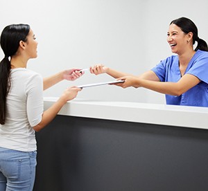 Patient smiling with dental staff while taking payment option paperwork