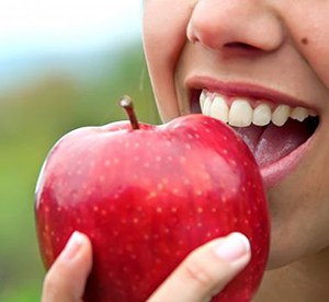 close-up of a person biting into a red apple
