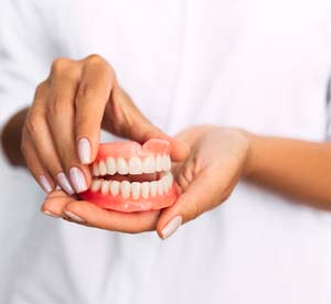 Woman holding full dentures