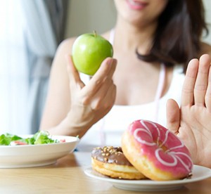 person choosing to eat an apple instead of donuts 