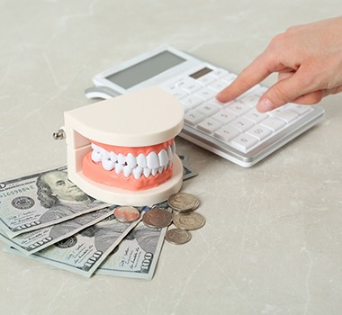 False teeth on stack of dollars next to calculator 