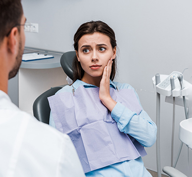 Woman experiencing toothache and talking to dentist