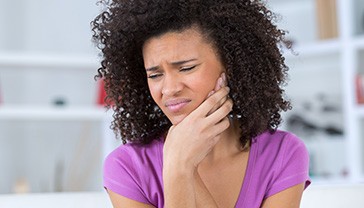 Woman holding cheek in pain