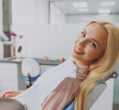 Woman leaning back in dental chair and smiling