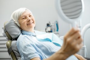 person looking at their dental implants in the mirror