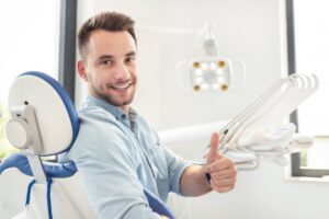 Man smiling and giving thumbs up at dentist
