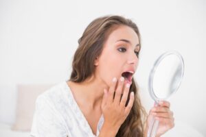 Woman looking at her dental crown in a mirror