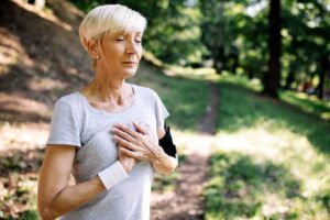 Senior woman touching her heart as she takes a deep breath